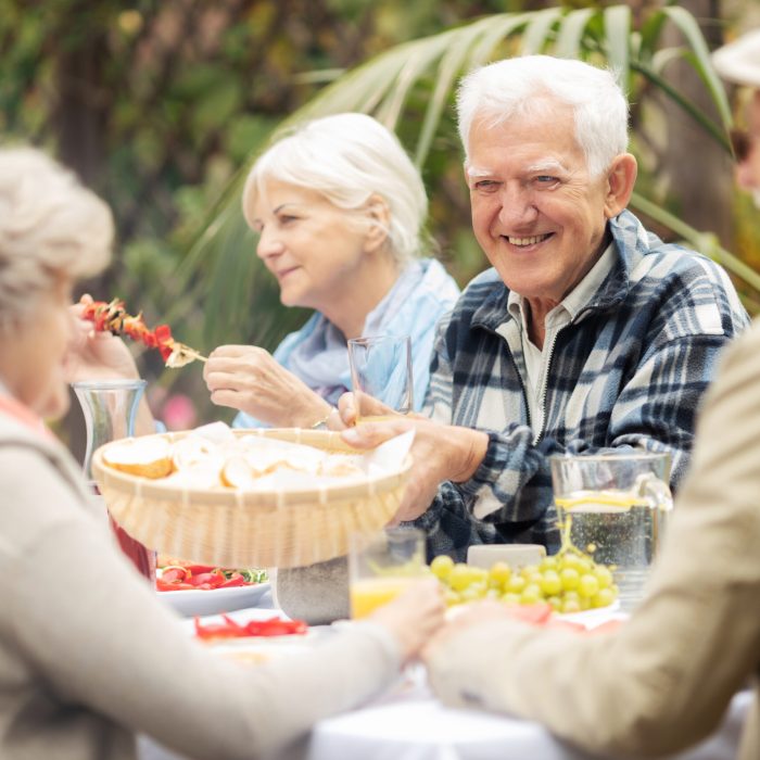 Group of senior friends eating grilled  food at the garden party